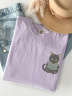 folded orchid Comfort Colors shirt featuring a black cat reading a book pocket print, cute bookworm apparel for readers, librarians, and cat lovers