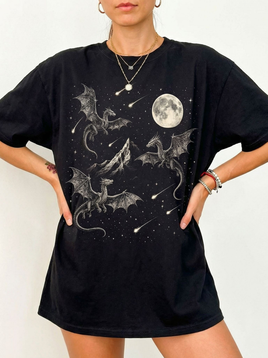 Black oversized t shirt with intricate dragon illustration showing dragons flying around a mountain with a full moon and star filled sky. Fantasy graphic tee for dragon lovers, book readers, and cozy dark academia aesthetic outfits.