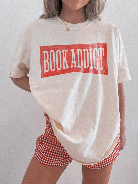 woman wearing an Ivory comfort colors t shirt with red vintage book addict text styled with denim and casual accessories