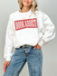 woman wearing a white sweatshirt with red vintage text that says book addict styled with blue jeans against a neutral background