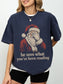 True Navy Comfort Colors shirt modeled with a retro Santa design and he sees what you’ve been reading phrase, a funny bookish Christmas tee for readers
