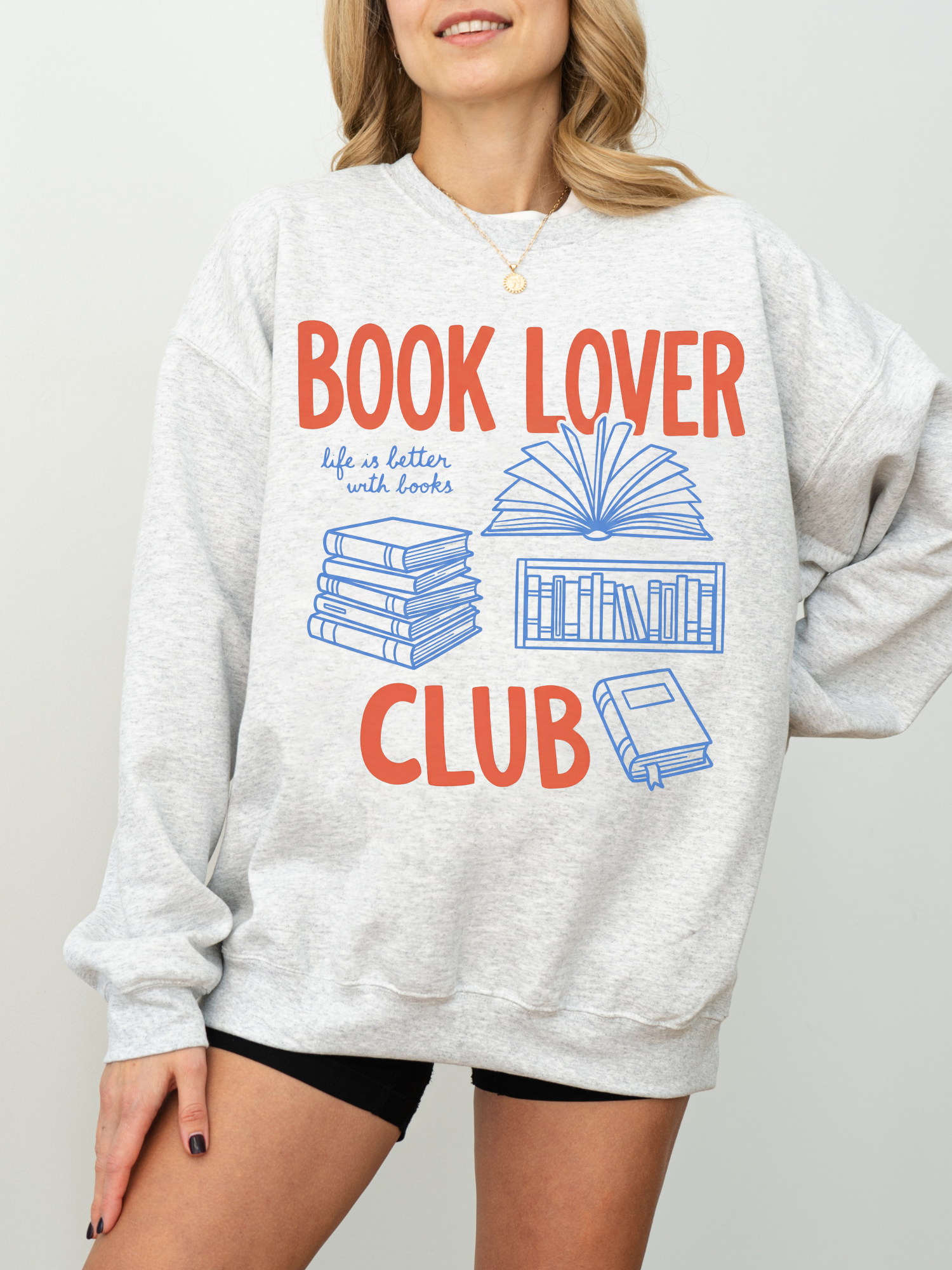 woman wearing an ash heather gray book lover club sweatshirt featuring books and reading themed graphics