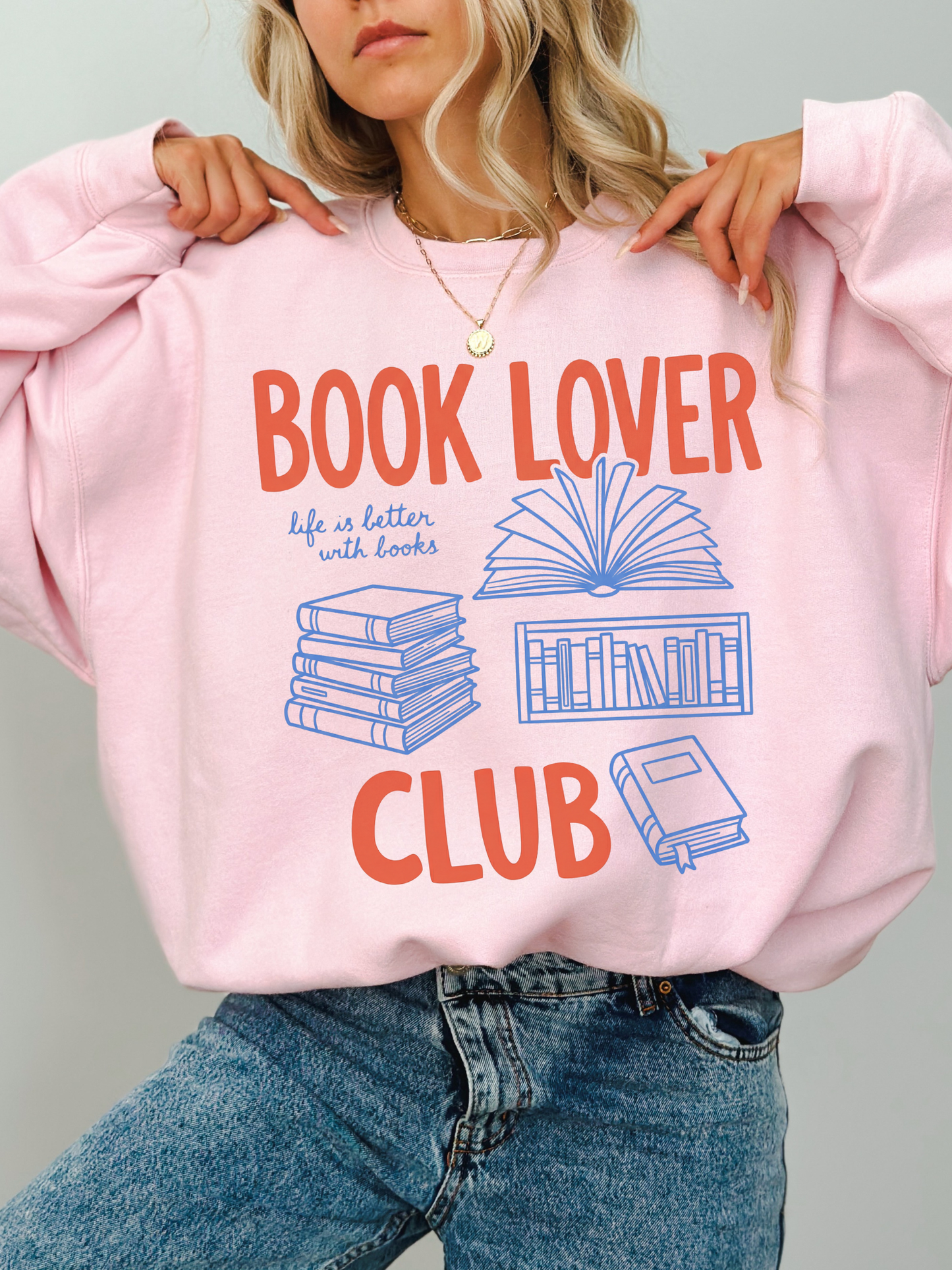 woman wearing a light pink book lover club sweatshirt with cozy reading graphic
