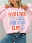 woman wearing a light pink book lover club sweatshirt with cozy reading graphic