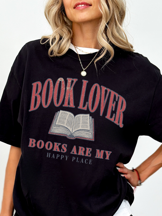woman wearing a black Comfort Colors book lover shirt with distressed book lover typography and open book design