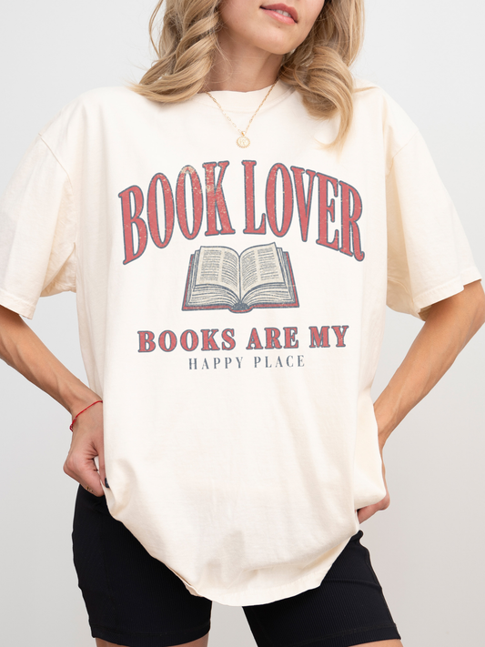 woman wearing an ivory Comfort Colors book lover shirt with vintage reading graphic and books are my happy place design