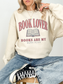 woman wearing a sand book lover sweatshirt with distressed book lover graphic and vintage reading design