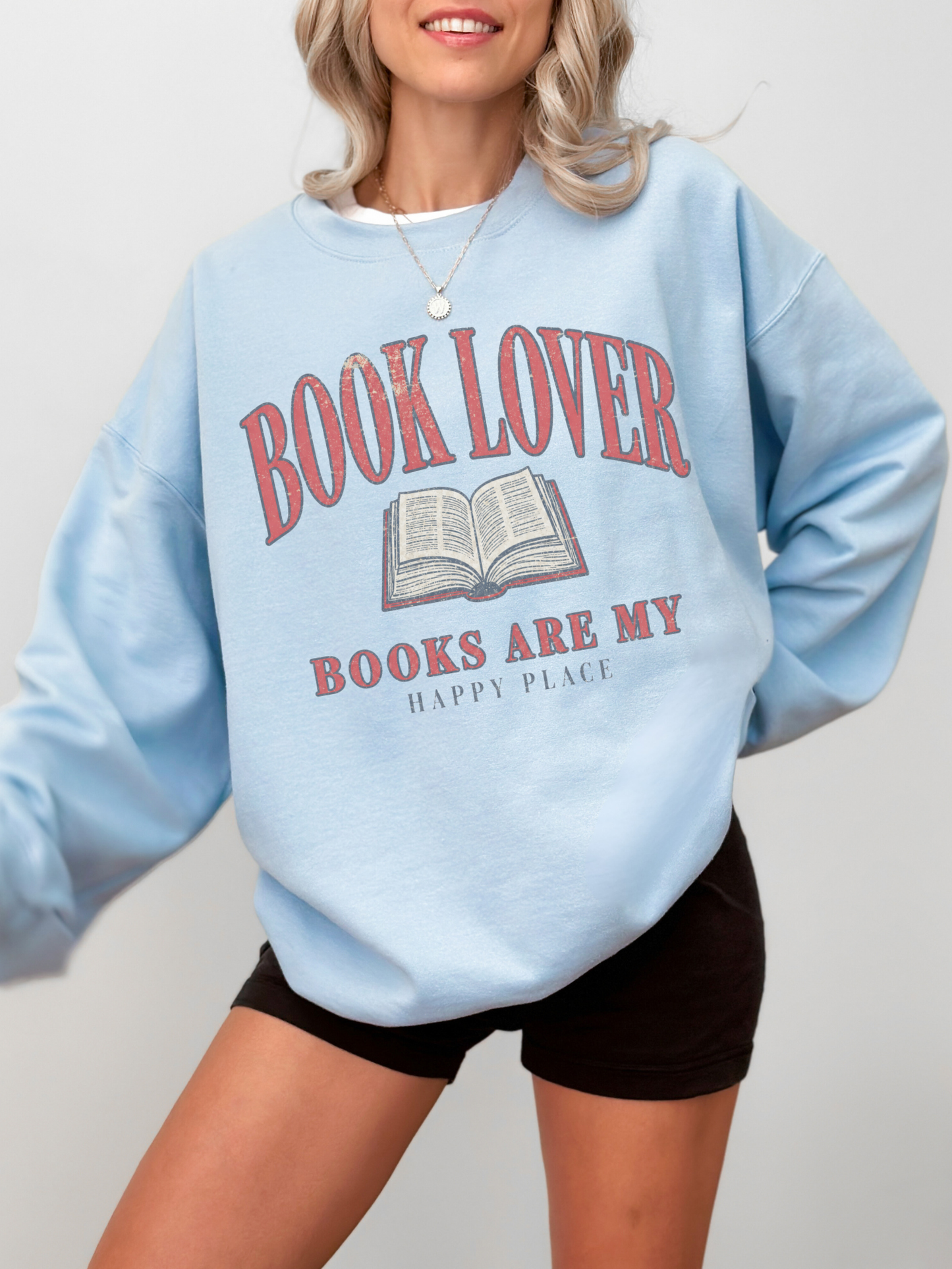woman wearing a light blue book lover sweatshirt with vintage reading design and open book illustration