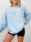 Woman wearing sky blue sweatshirt with “book lover” and bow design, styled for bookish readers