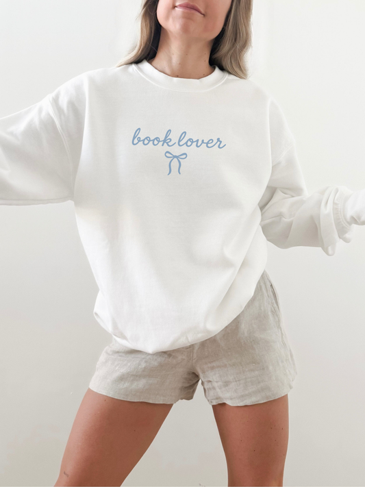 Cozy white “book lover” sweatshirt with coquette bow, modeled casually in soft natural light