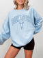 Woman wearing baby blue Book Lover varsity sweatshirt with coquette bow design, styled with black shorts