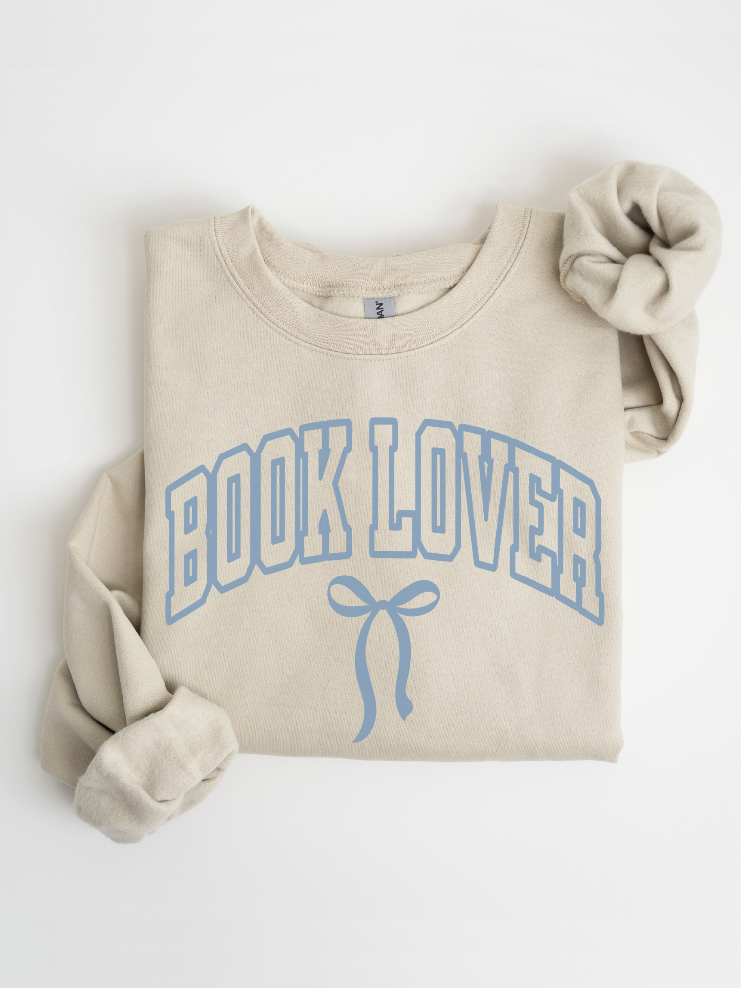 Folded sand-colored Book Lover varsity sweatshirt with blue bow design on white background