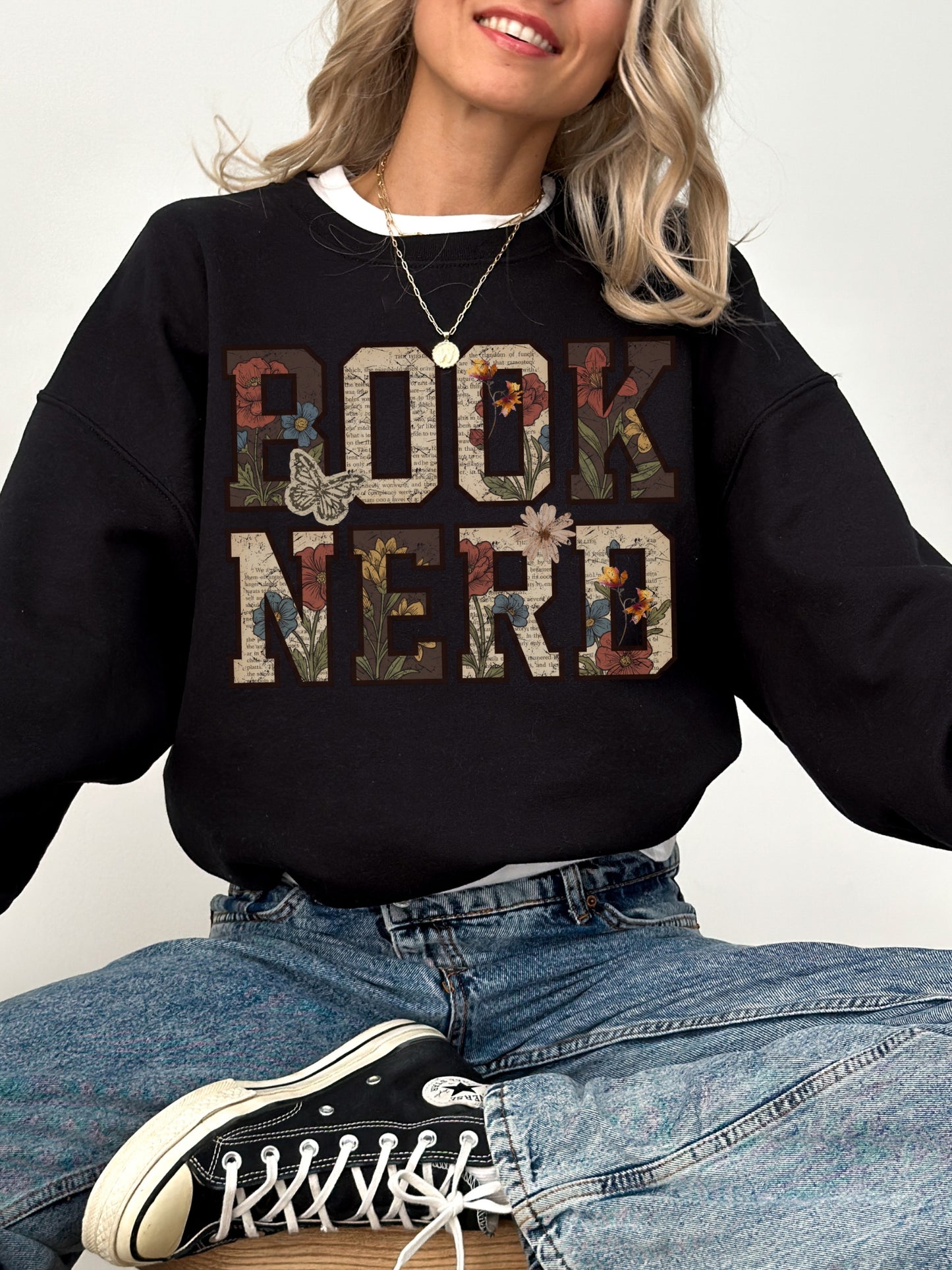 Black Gildan sweatshirt modeled with a vintage floral Book Nerd design featuring book pages, flowers and butterflies, bookish sweatshirt for readers and book lovers