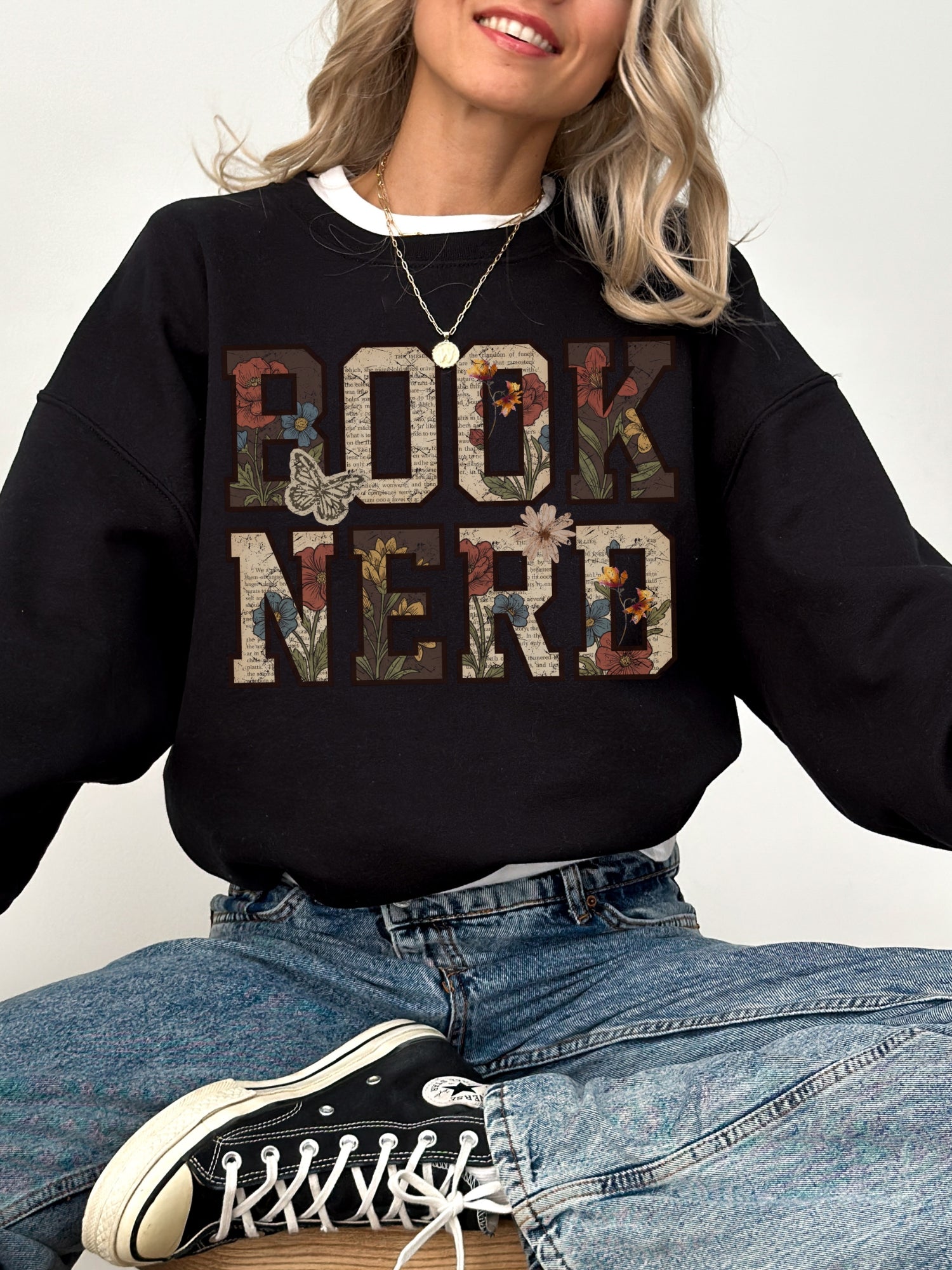 Black Gildan sweatshirt modeled with a vintage floral Book Nerd design featuring book pages, flowers and butterflies, bookish sweatshirt for readers and book lovers