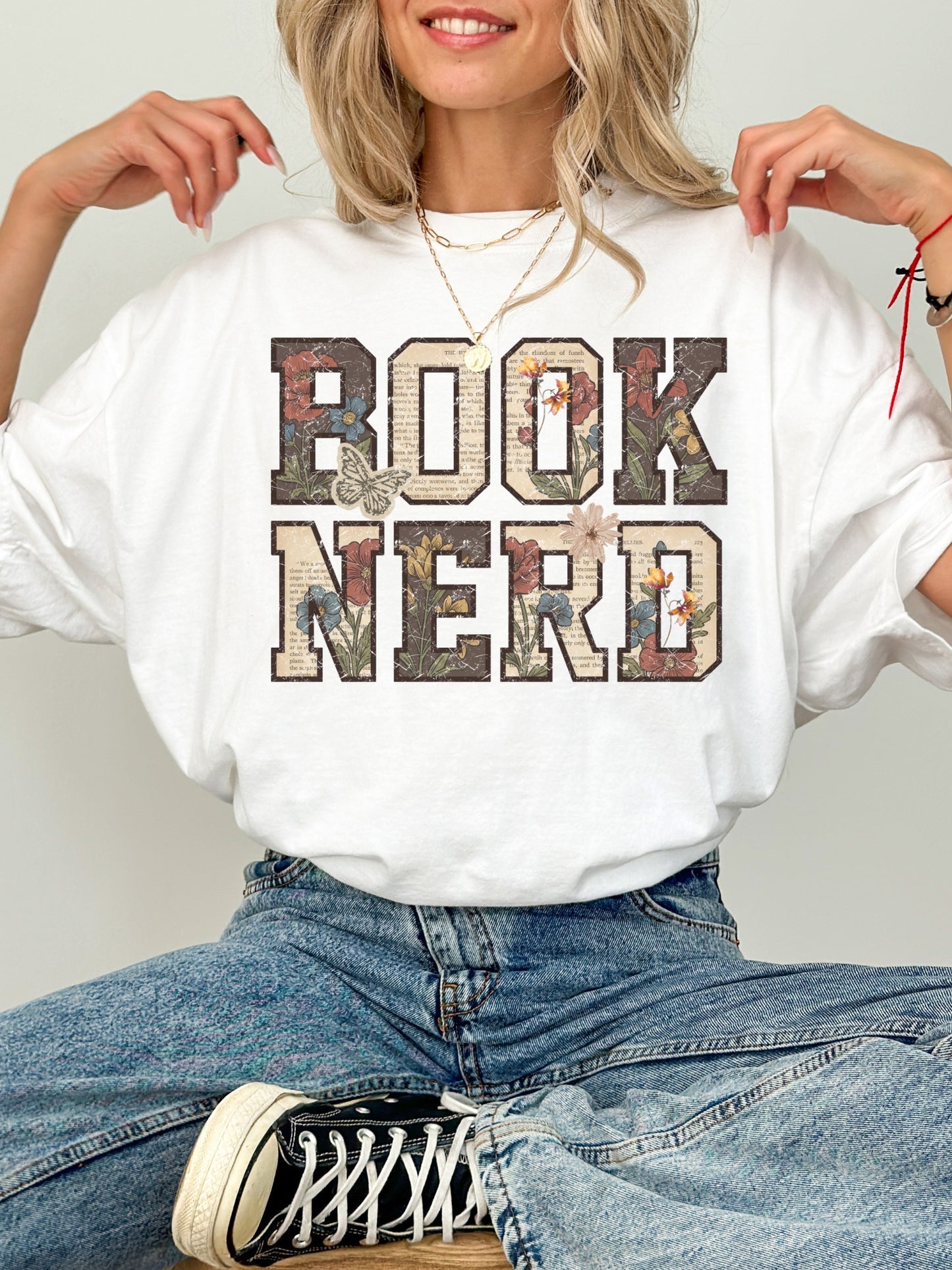 White Comfort Colors shirt featuring a vintage floral Book Nerd design with book page lettering, wildflowers and butterflies, bookish t shirt for readers and book lovers