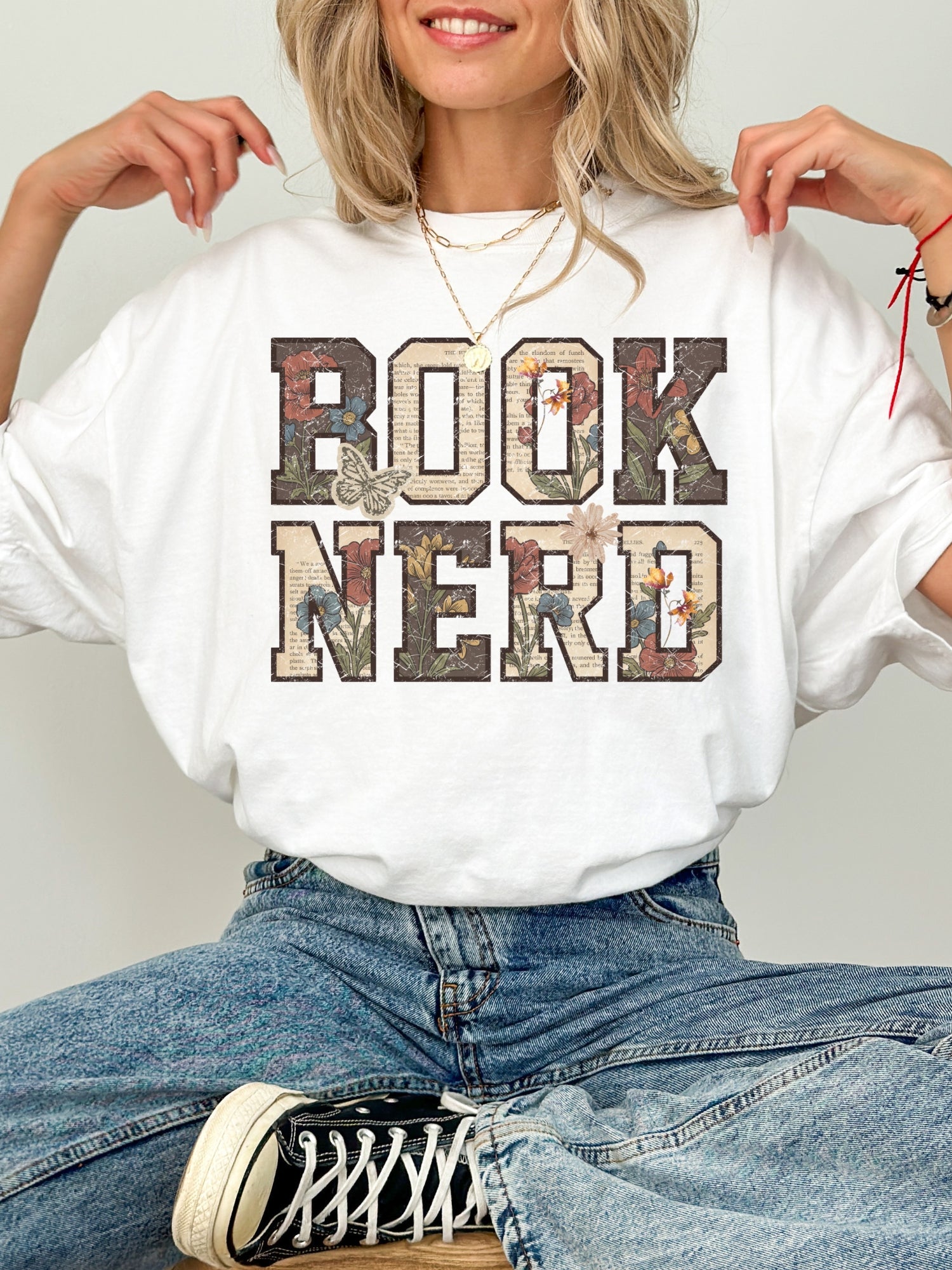 White Comfort Colors shirt featuring a vintage floral Book Nerd design with book page lettering, wildflowers and butterflies, bookish t shirt for readers and book lovers