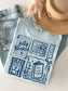 flat lay folded mockup of a blue chambray shirt featuring 5 book themed stamps