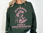 forest green sweatshirt with pink print of retro woman reading and text about book hangover