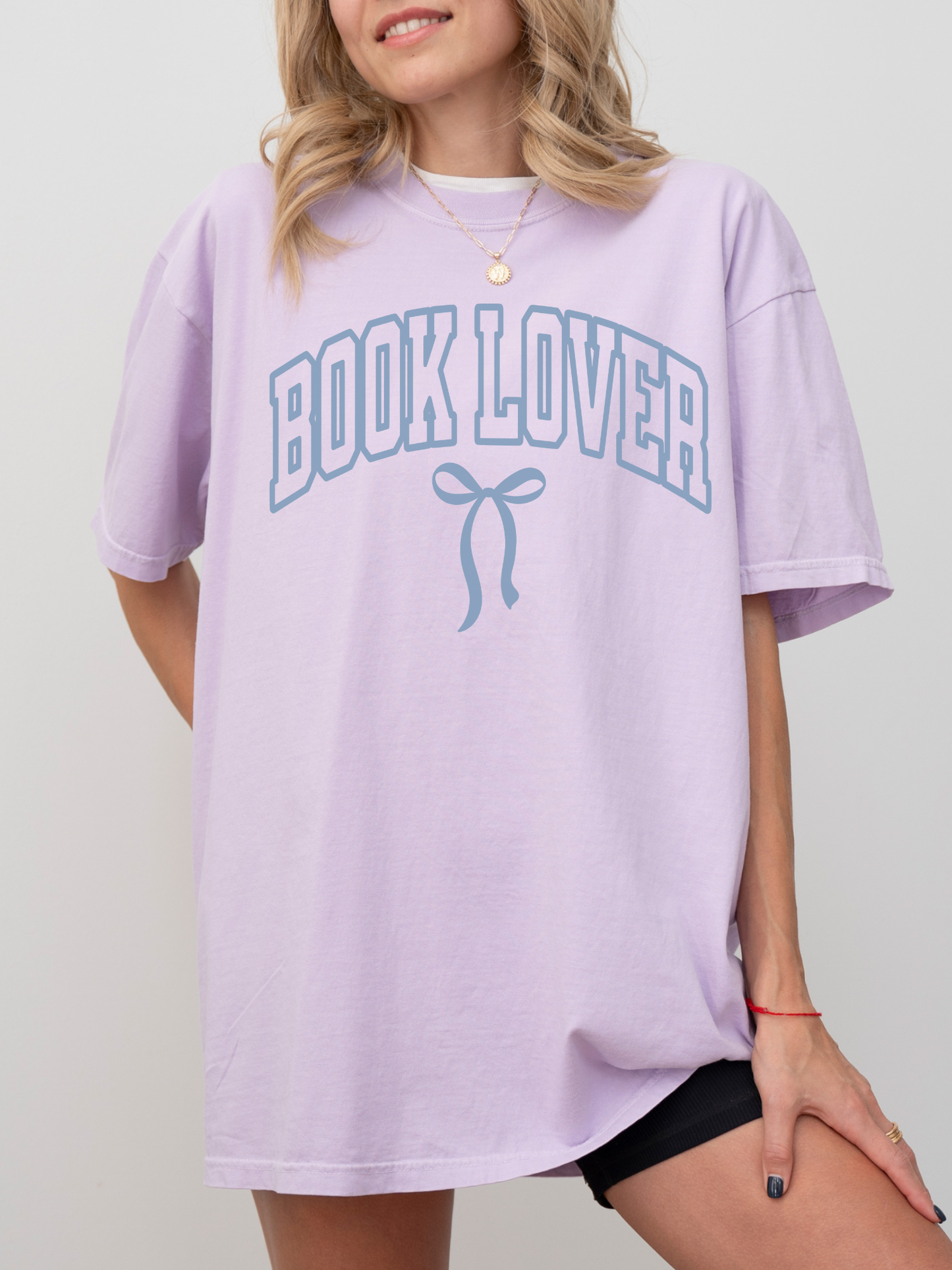 girl wearing a lavender t-shirt that says Book Lover with a bow in varsity block font