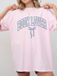 girl wearing a light pink t-shirt that says Book Lover with a bow in varsity block font