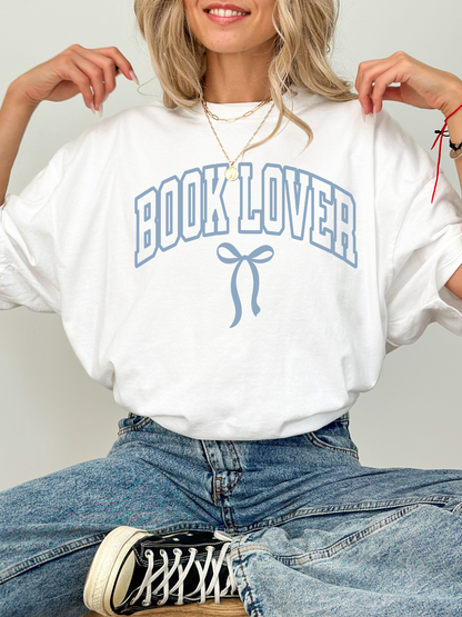 girl wearing a white t-shirt that says Book Lover with a bow in varsity block font