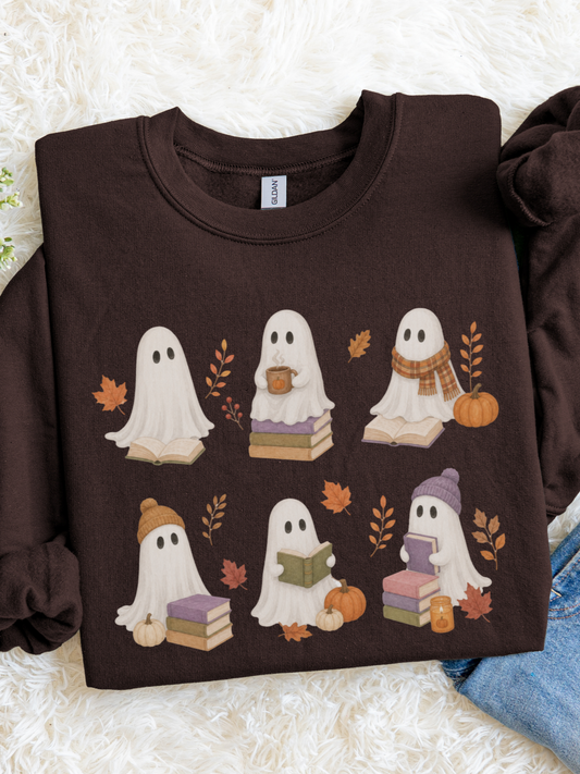 A dark chocolate long-sleeve crewneck sweatshirt featuring a cute cartoon ghost graphic with autumn details, laid flat on a white faux fur background.