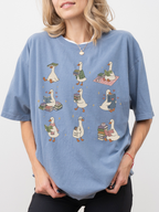 woman wearing blue jean comfort colors shirt with adorable reading geese illustration carrying books and cozy book lover artwork