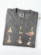 folded pepper comfort colors book lover goose shirt featuring cute ducks reading books carrying novels and cozy reader aesthetic artwork