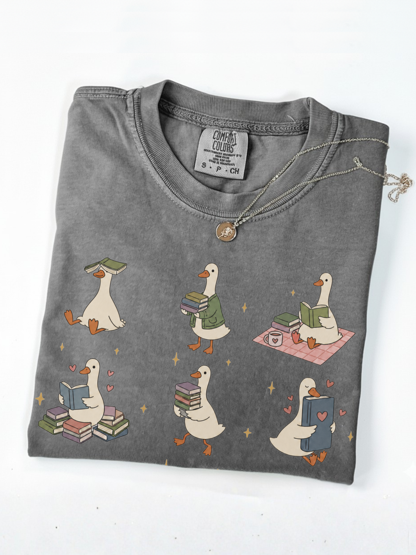folded pepper comfort colors book lover goose shirt featuring cute ducks reading books carrying novels and cozy reader aesthetic artwork