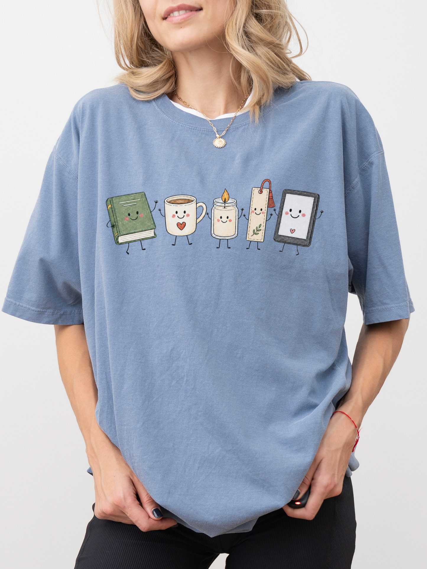 Comfort Colors bookish shirt featuring smiling book, coffee, candle, bookmark and e-reader illustration in Blue Jean