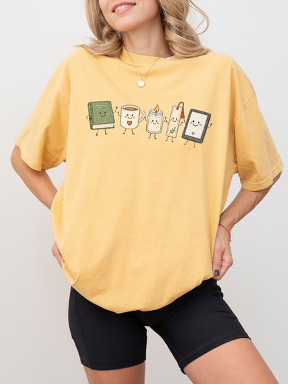 Comfort Colors bookish reader shirt with book, coffee, candle, bookmark and e-reader illustration in Mustard