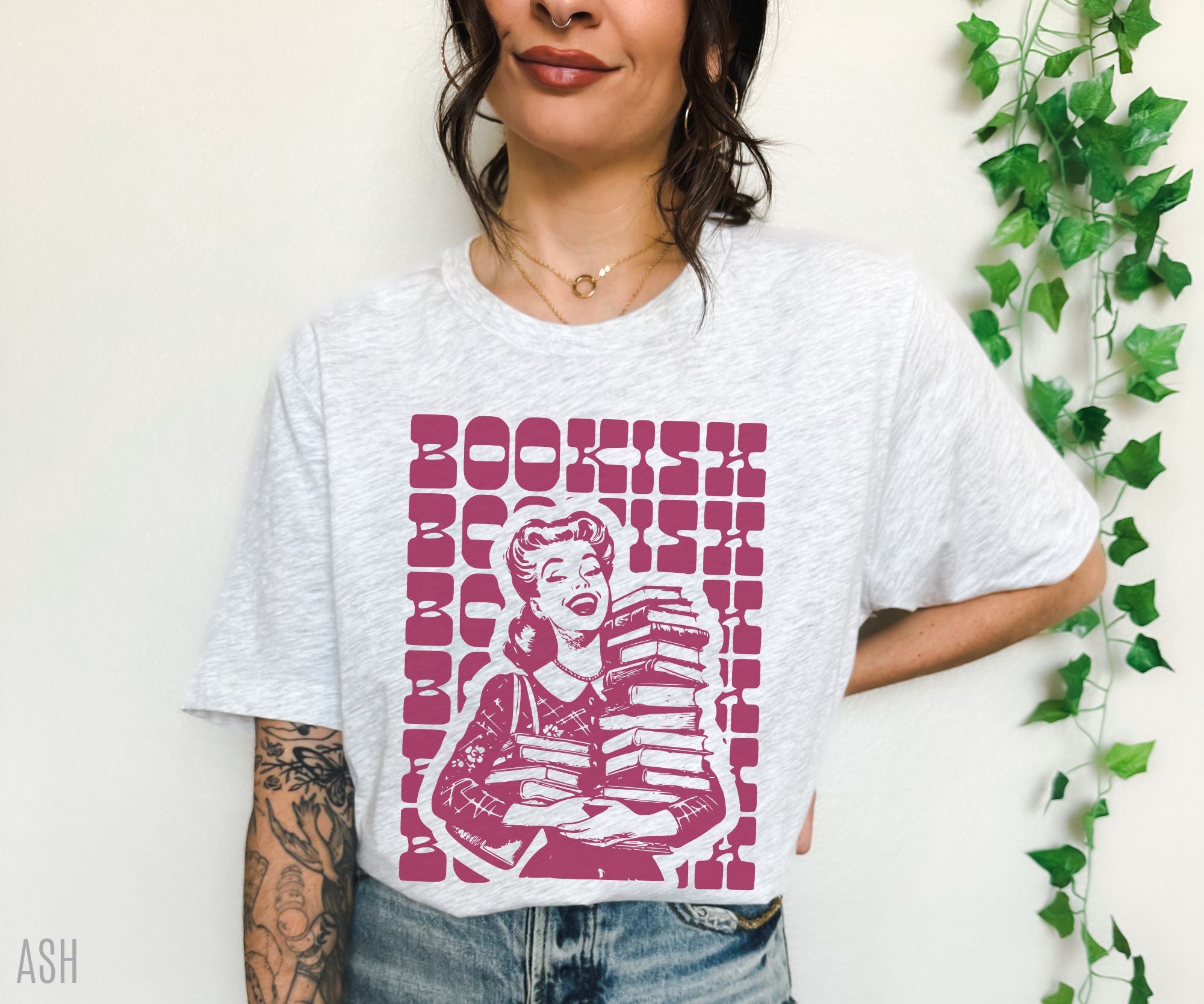 woman in ash grey t-shirt with pink retro graphic of girl holding books and repeated bookish text