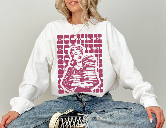woman sitting cross-legged in white bookish sweatshirt with vintage magenta girl and books design