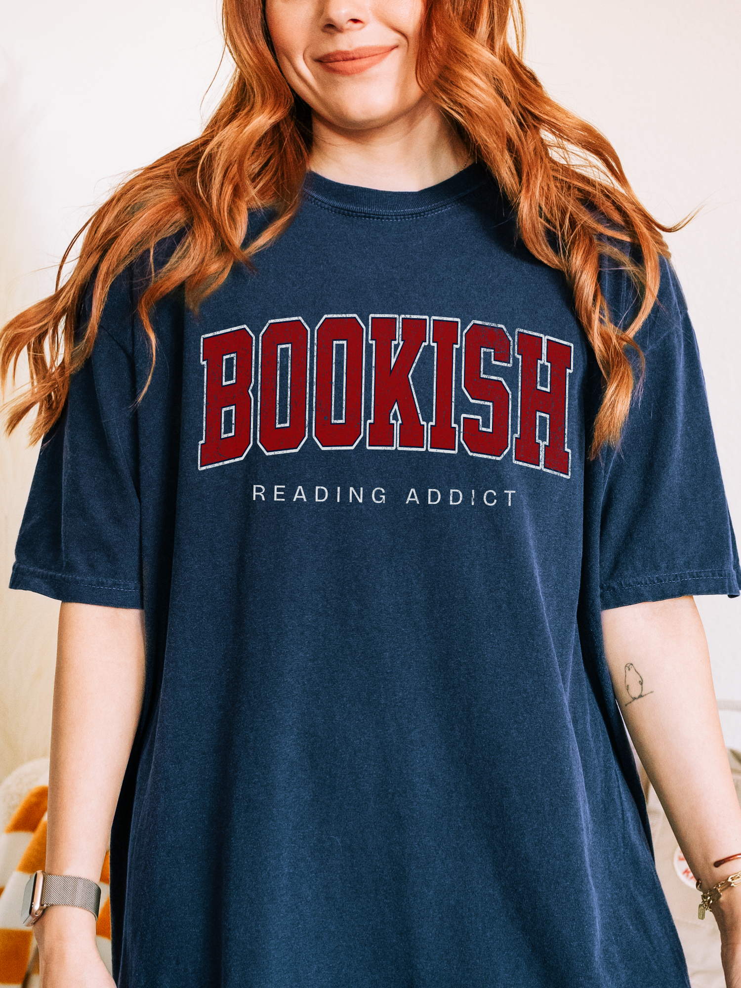 woman wearing navy Comfort Colors shirt that says Bookish Reading Addict in large red varsity print