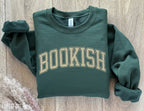 folded forest green sweatshirt that says bookish in vintage varsity font on wood floor