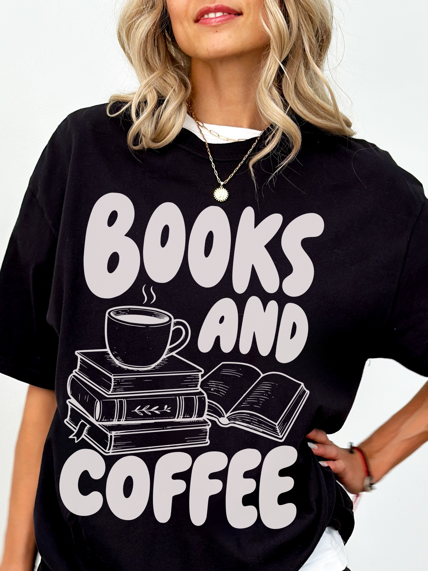 woman wearing a black Comfort Colors shirt featuring a books and coffee graphic with stacked books, open book, and steaming coffee cup illustration, oversized bookworm shirt perfect for readers librarians and coffee lovers