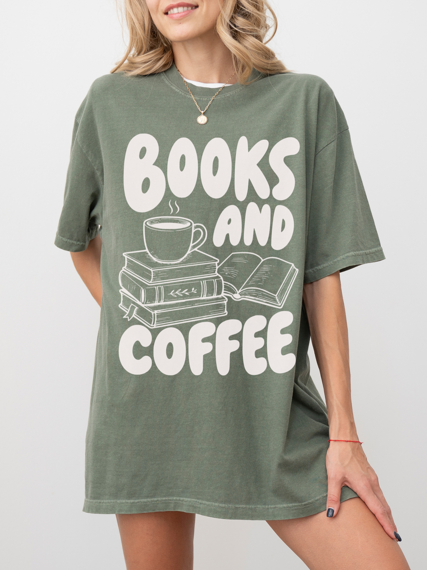 woman wearing a moss Comfort Colors shirt featuring a books and coffee graphic with a steaming coffee mug, stacked books, and open novel illustration, oversized reading shirt for book lovers