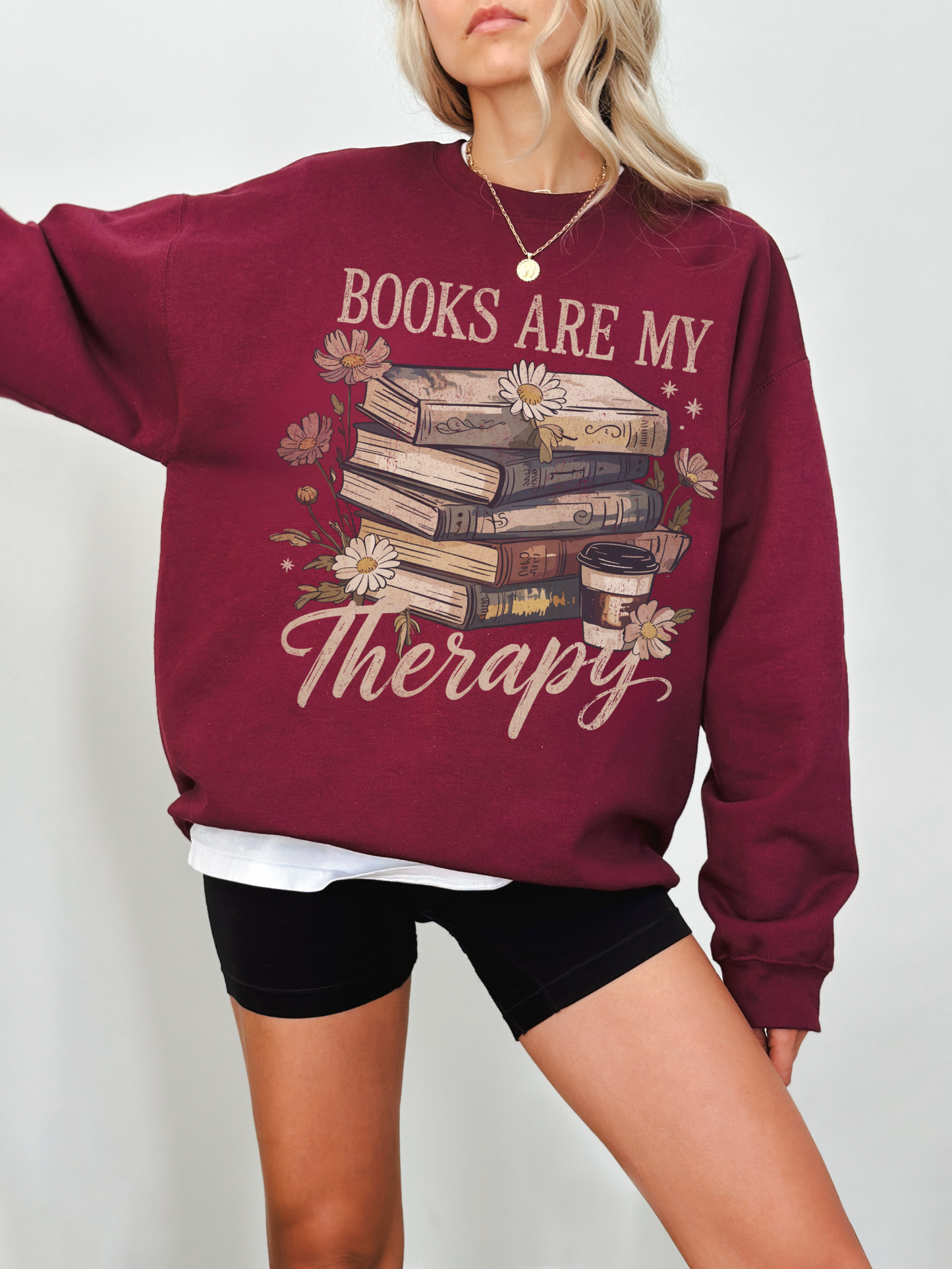 burgundy books are my therapy sweatshirt with coffee and floral book stack design worn by woman with blonde hair