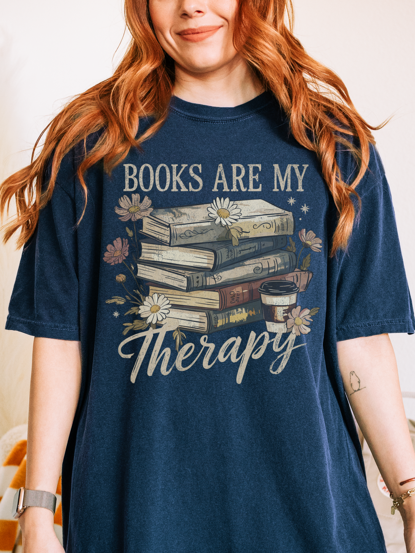 Woman in navy blue Books Are My Therapy shirt standing indoors with vintage style reader design and flowers