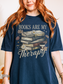 Woman in navy blue Books Are My Therapy shirt standing indoors with vintage style reader design and flowers