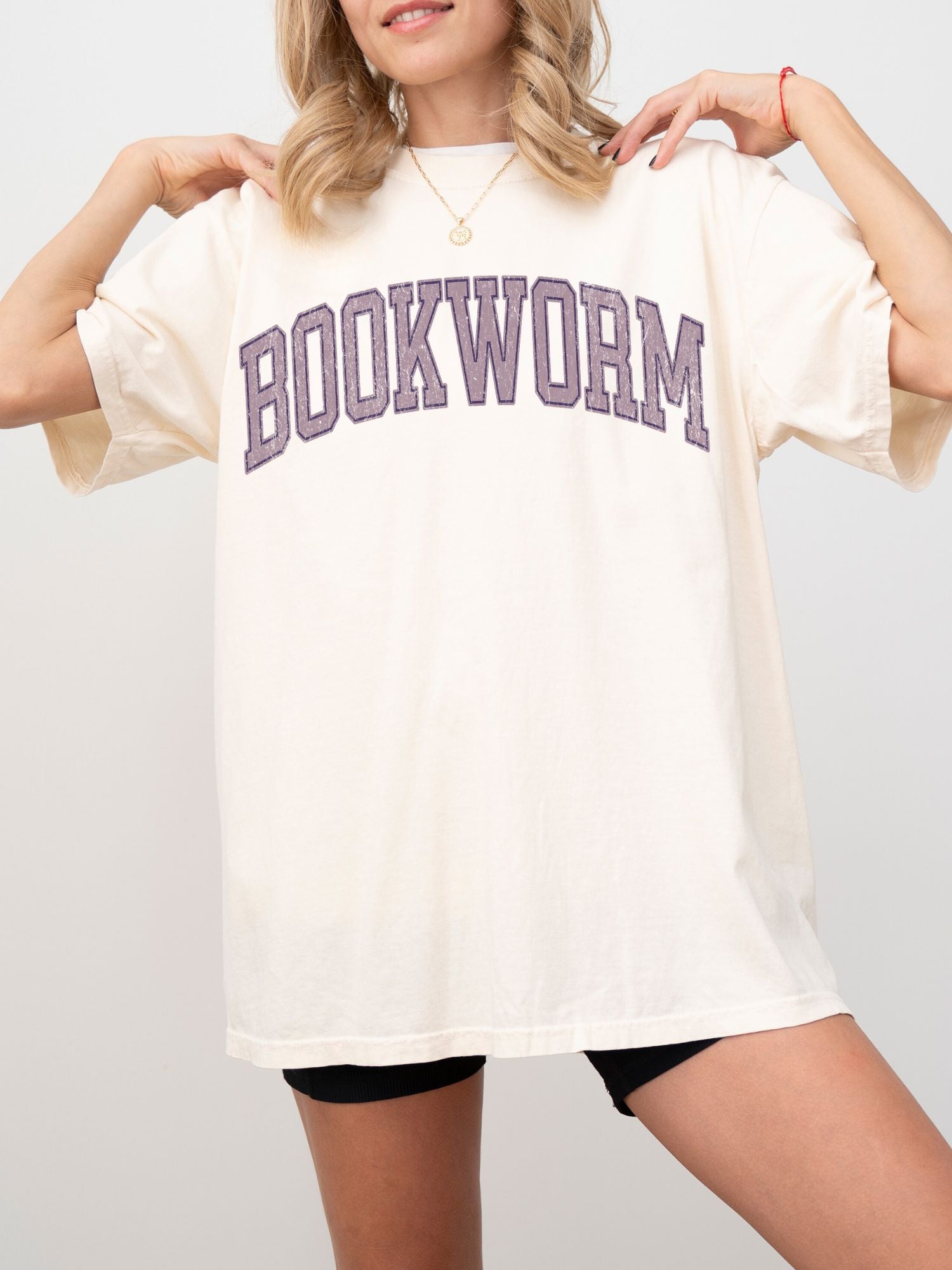 woman in ivory shirt with bold purple bookworm text in vintage varsity college lettering
