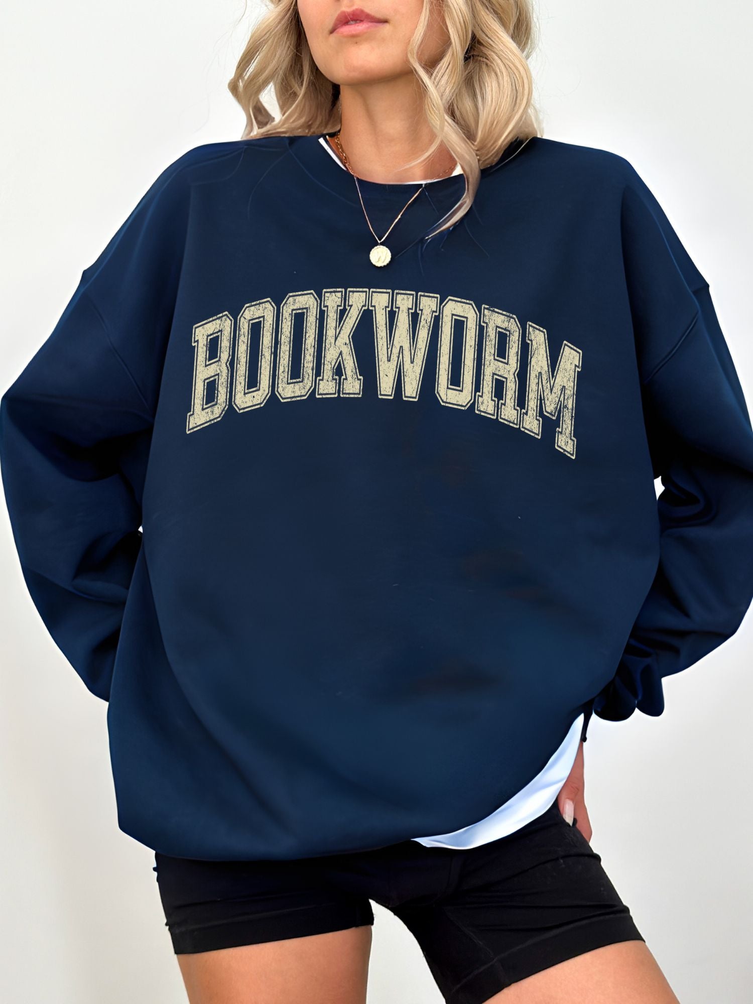 girl standing wearing a navy sweatshirt that says "bookworm" across the top in a jersey sport font