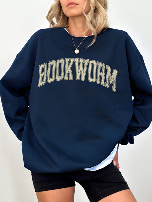 girl standing wearing a navy sweatshirt that says "bookworm" across the top in a jersey sport font