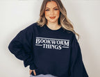 woman wearing navy sweatshirt that says bookworm things in a retro font 