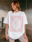 Woman wearing a cream oversized t shirt with pink striped vintage frame graphic and text buy me books and tell me I’m pretty styled casually indoors