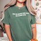 woman wearing light green shirt that says buy me books and call me a good girl standing in front of plant print wall art