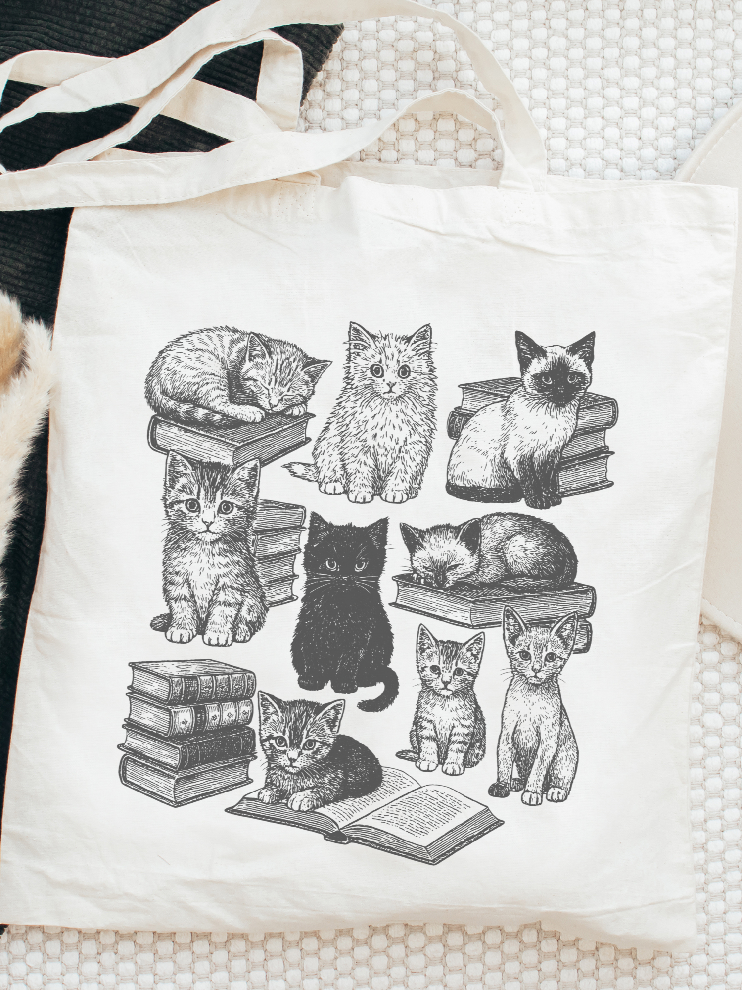 aesthetic bookish tote bag with illustrated cats lounging and reading on books, styled flat on a textured white background