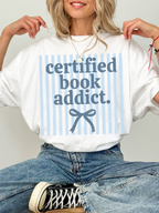 model wearing certified book addict oversized shirt with blue stripe design and bow detail styled with jeans and sneakers