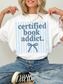 model wearing certified book addict oversized shirt with blue stripe design and bow detail styled with jeans and sneakers