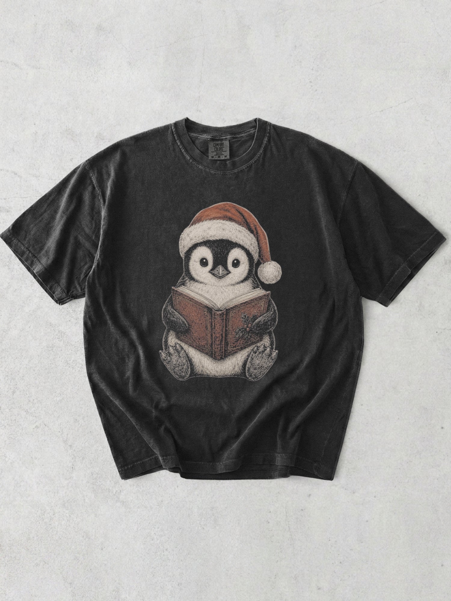Graphite Comfort Colors bookish shirt featuring a cute penguin wearing a Santa hat and reading a Christmas book for readers and book lovers